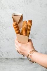 Woman taking churros from a cone and dipping it in chocolate sauce