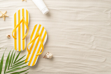 Top view of idyllic sunbathing. Beach essentials—yellow flip-flops, sunscreen, seashells,...