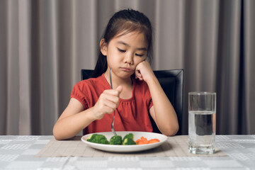 Obraz na płótnie Canvas Little cute kid girl refusing to eat healthy vegetables. Children do not like to eat vegetables.