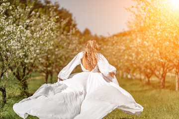 Woman white dress park. A woman in a white dress runs through a blossoming cherry orchard. The long...