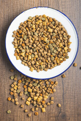 Dry kibble pet food. Dog or cat food in bowl on wooden table. Top view.