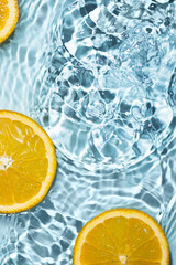 Creative summer background with orange fruit slices in swimming pool water. Summer wallpaper with copy space.