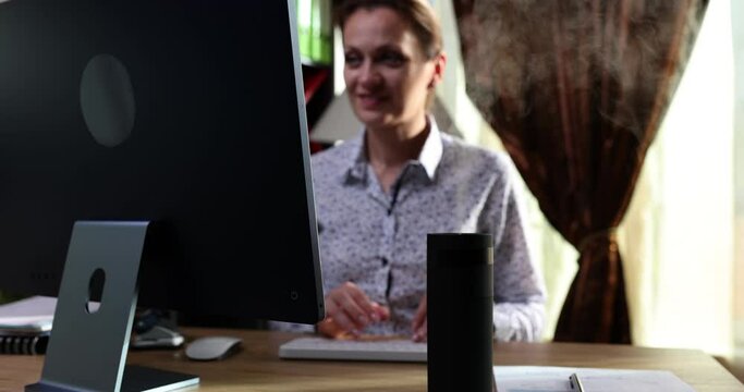 Humidifier during a seated workplace woman using computer work. Manager enjoying the scent of aromatherapy steam from essential oil diffuser