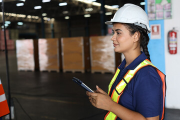 Fototapeta premium Warehouse workers woman with hardhats and reflective jackets using tablet, walkie talkie radio while looking away and controlling stock and inventory in retail warehouse logistics, distribution center