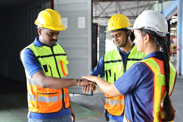 Group of engineer or worker in protective suit with hardhat standing and stacking hands celebrate successful together or completed deal commitment at heavy industry manufacturing factory or warehouse