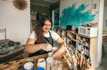 Smiling potter mixing paint at workshop