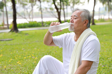 Obraz premium Healthy asian senior man drink water after practice yoga exercise tranining for healthy while looking at camera and smile in park outdoor. Happy elderly sport outdoor lifestyle concept