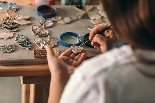 Potter painting ceramic object at workshop