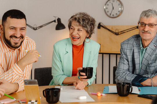 Colleagues sitting at table laughing and talking with each other