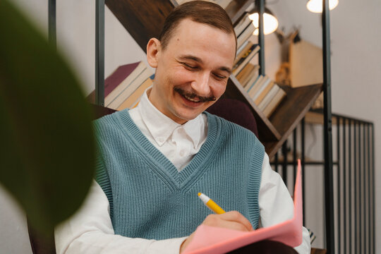 Smiling man with moustache taking notes sitting in studio