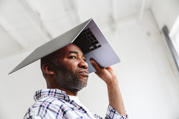 Bored businessman carrying laptop on head