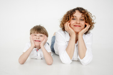 Mother and son leaning on elbows lying in front of white backdrop