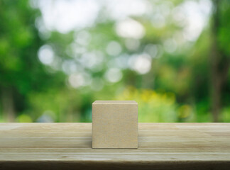 Wood block cube on wooden table over blur green tree in park