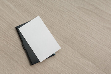 A green metal business card case and a white horizontal business card are placed on the table. blank card, mockup