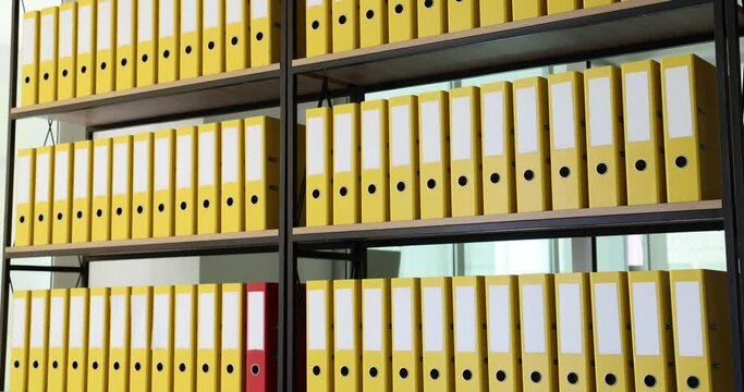 Red folder moves quickly in shelf among yellow ones. Finding the desired folder in the archive