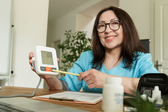 Smiling doctor showing digital display of blood pressure gauge