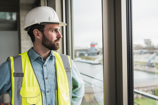Building contractor looking out of window at site