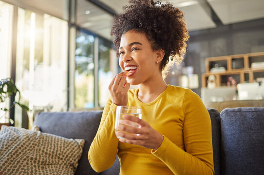 Glass, water and woman with medicine on sofa for health, self care and supplement at home. Relax, healthcare and happy african person with liquid drink and pill or tablet for wellness on couch