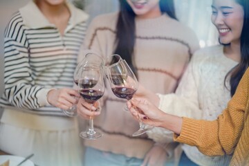 Cheerful friends enjoying home Birthday holiday party. Asian Friends cheering drinking red wine celebrating Christmas or New Year party