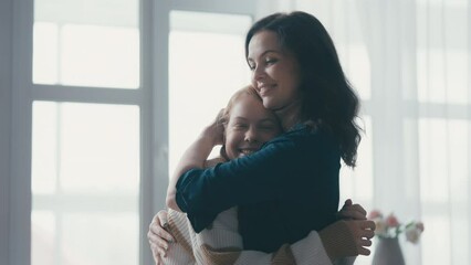 Happy teen girl hugging loving mother at home, trustful family relationship