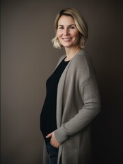 Obraz premium Portrait of a beautiful pregnant woman wearing a gray sweater and black pants