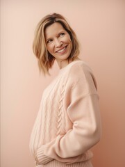 Portrait of a smiling young woman in a sweater on a pink background