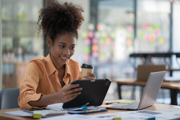 Confident ethnic businesswoman using a digital tablet and a laptop at work.