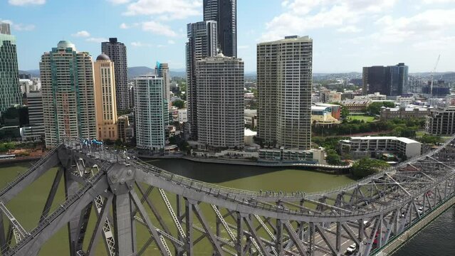 Aerial view over Brisbane Story Bridge with walkers climbing to the top, then panning across the bridge and circling back around with a view over Captain Burke Park and surrounds.