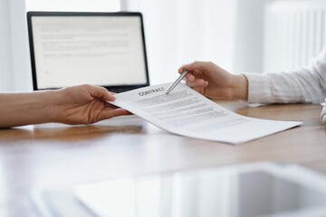 Businesswoman lawyer pointing into contract special points admitting something for colleague or client at the wooden desk in office. Business people teamwork and partnership, meeting concept.