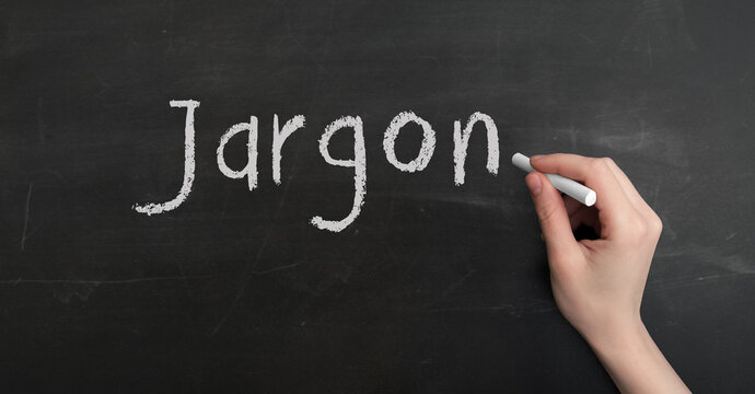 A woman's hand write text jargon with chalk on chalkboard