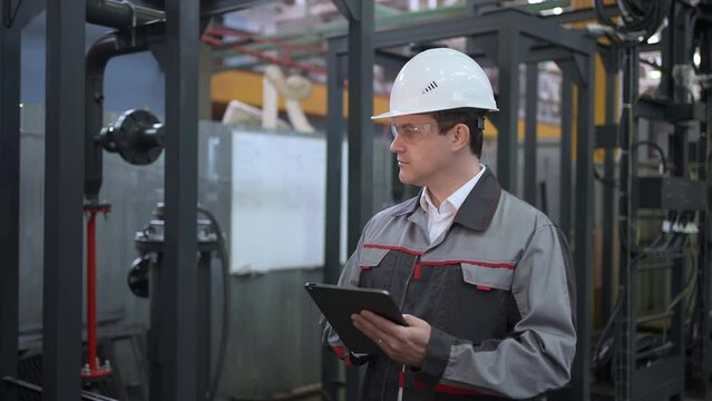 Engineer man walking Heavy industry plant using Technology tablet computer Factory for Oil, Gas Fuels Transport Pipeline, Professional worker Industrial checking production metal construction