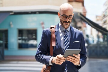 Young hispanic man executive smiling confident using touchpad at street