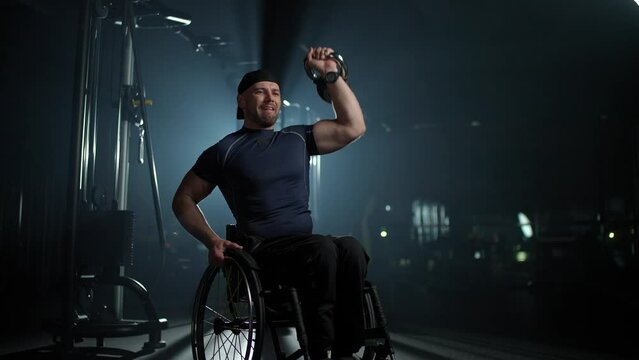 Disabled athlete in wheelchair performs exercises with dumbbells, gym training and physical activity, people with disabilities, motivation.