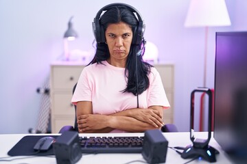 Mature hispanic woman playing video games at home skeptic and nervous, disapproving expression on face with crossed arms. negative person.