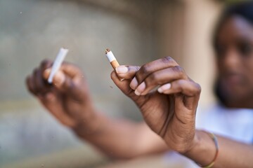 Young african american woman breaking cigarette at street