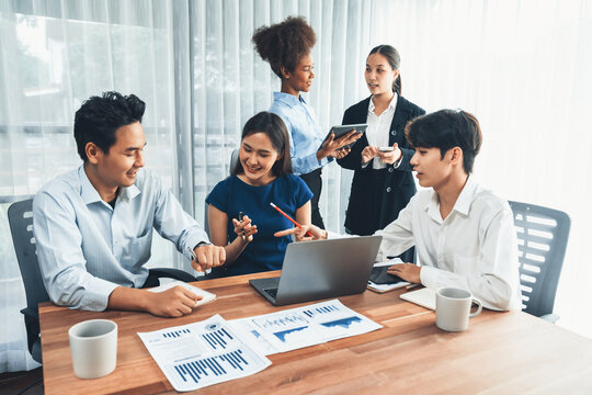 Multiracial analyst team use BI dashboard data to analyze financial report on meeting table. Group of diverse business people utilize data analysis by FIntech for success business marketing. Concord