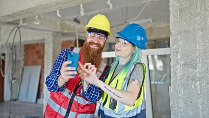 Man and woman builders using smartphone working at construction site