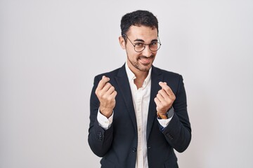Handsome business hispanic man standing over white background doing money gesture with hands, asking for salary payment, millionaire business