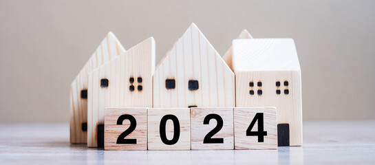 2024 Happy New Year with house model on table wooden background. Banking, real estate, investment,...