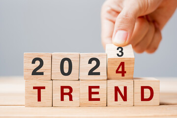 hand flipping block 2023 to 2024 TREND text on table. Resolution, idea, goal, motivation, reboot,...
