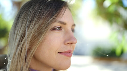 Obraz premium Young blonde woman looking to the side with relaxed expression at park