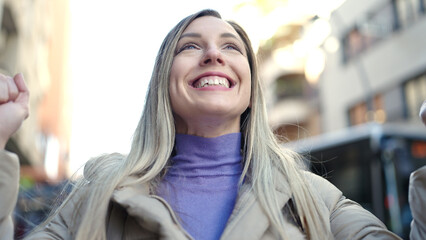 Young blonde woman smiling confident standing with winner expression at street