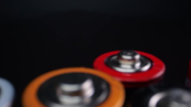 Camera zooms in on used alkaline batteries, commonly used in electronic devices. Filmed in macro on a dark surface.