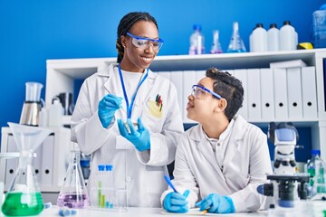 African american mother and son scientists smiling confident working laboratory