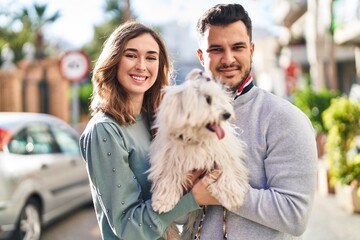 Man and woman holding dog standing together at street