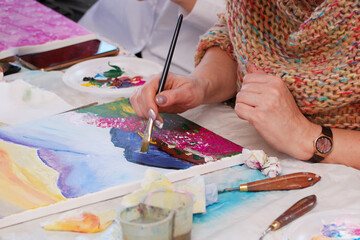 A woman paints a picture on canvas with a brush. Master Class . creative hobby