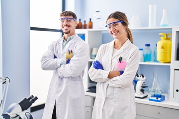 Young man and woman scientists workers standing with arms crossed gesture at laboratory