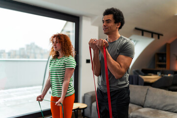 An interracial couple curl ups together in the living room, is dressed casually and they like to exercise together