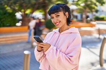 Young woman smiling confident using smartphone at park