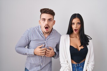 Young hispanic couple standing over white background afraid and shocked with surprise and amazed expression, fear and excited face.